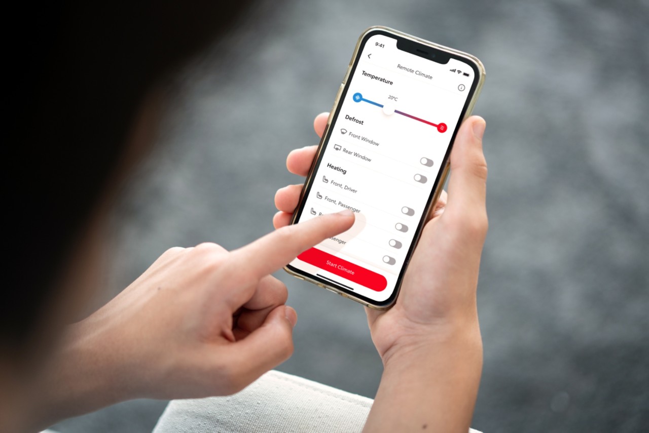 Inimene hoiab käes nutitelefoni, milles on näha MyToyota rakendus. Ta puudutab vasaku käega ekraani, et seadistada telefonist oma auto kliimaseadet.